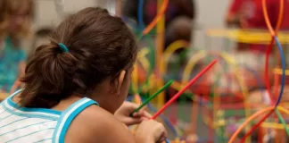 Menina com os cabelos presos brinca na escola.