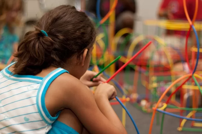 Menina com os cabelos presos brinca na escola.