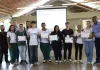 Estudantes com seus certificados em mãos posam para foto ao lado de convidados.