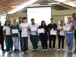 Estudantes com seus certificados em mãos posam para foto ao lado de convidados.