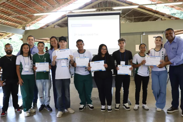 Estudantes com seus certificados em mãos posam para foto ao lado de convidados.