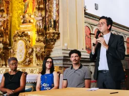 Padre Geraldo fala ao microfone para o público presente.