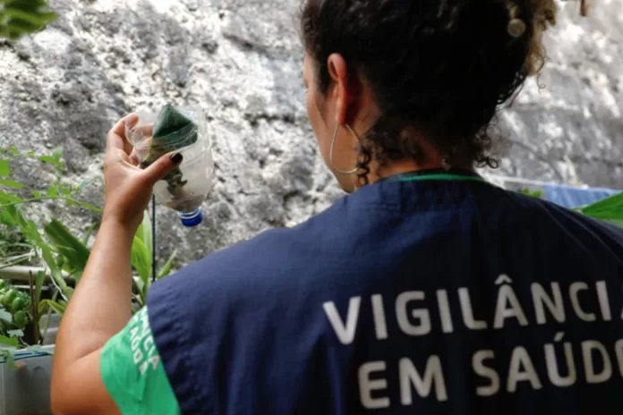 Agente de Vigilância em Saúde observa potes com água parada em casa de morador.